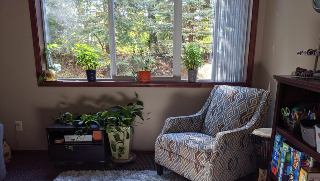a lounge chair by the window with potted plants
